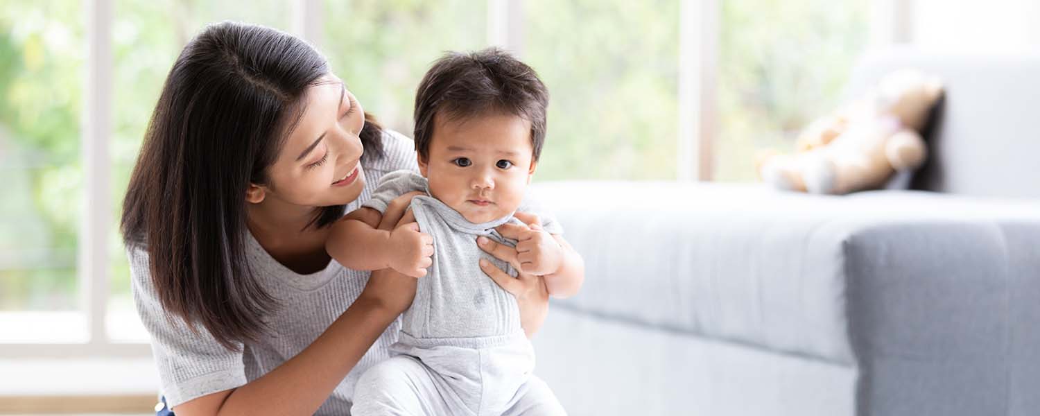 Young mother playing with her baby inside a house