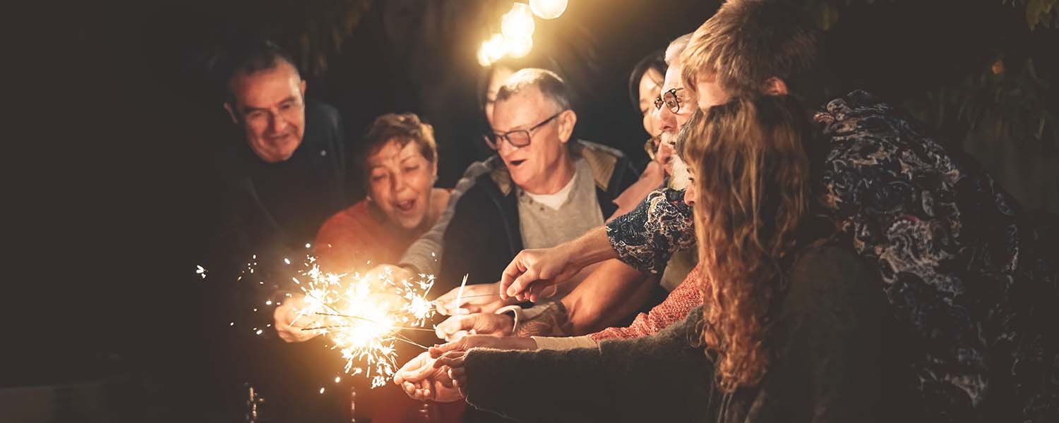 Diverse range of people lighting sparklers outside at night